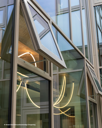 Moderne bygningsfasade med kantete glassvinduer, noen åpne, som reflekterer neonlys og viser frem moderne arkitektonisk design.