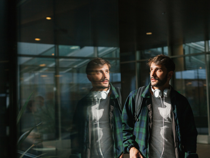 Ung mann reflektert i en glassvegg